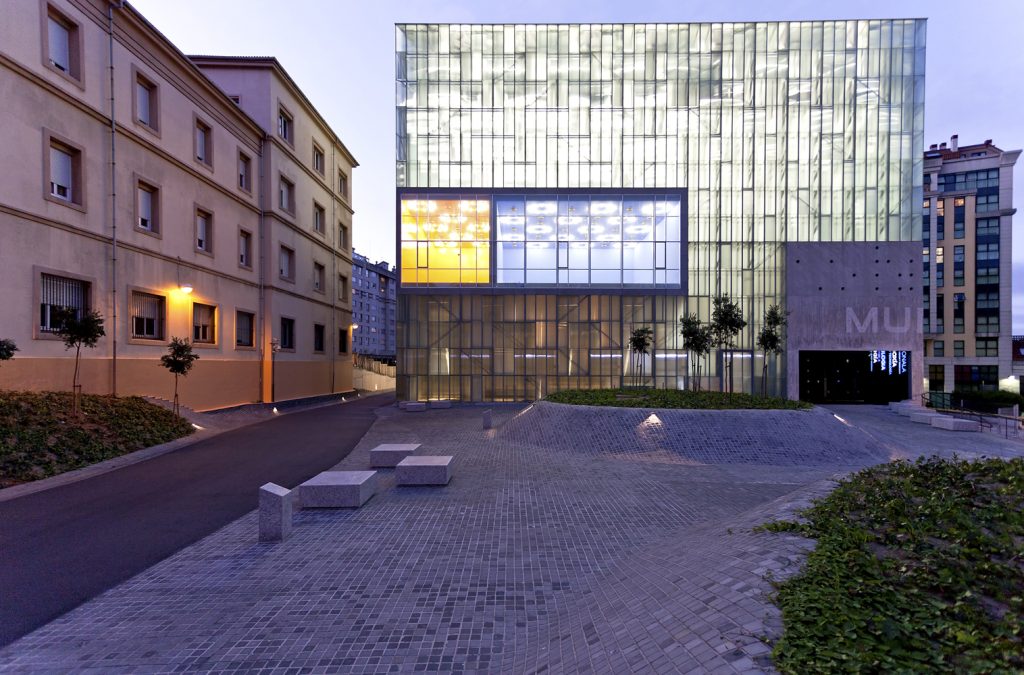 National Museum of Science and Technology - AceboXalonso - Modern glass building with illuminated interiors, between traditional architecture during the evening