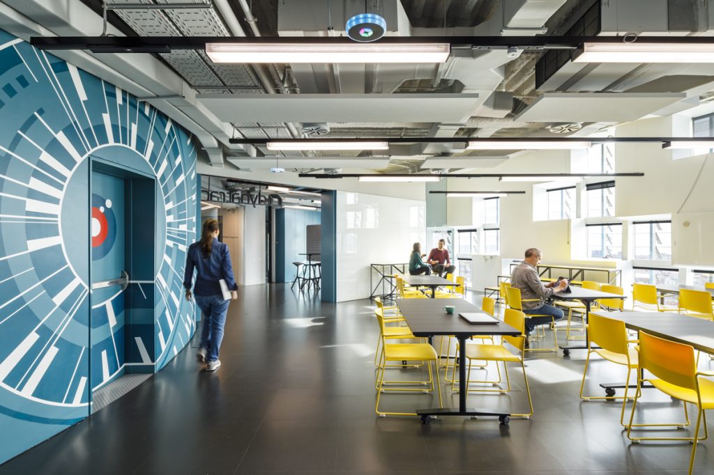 Dynatrace Lab Barcelona Floor 15 - Planet Architects - Vibrant office space, characterized by an artistic wall design, bright lighting, and functional furniture