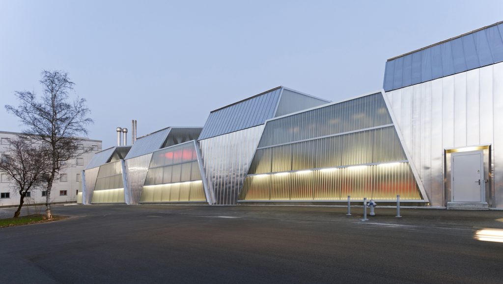 Bernmobile Tramdeposit in Bern - Penzel Architektur - Sleek angular metallic building at twilight, reflecting the day’s last light