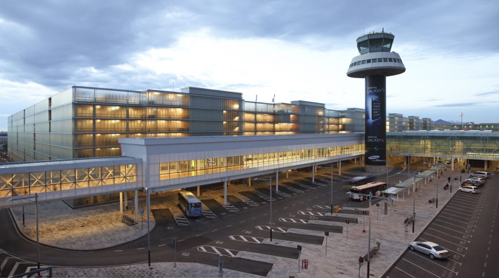 El Prat de Llobregat Airport Parking - Ricardo Bofill Taller de Arquitectura - Modern airport terminal at dusk highlighted by its illuminated glass facade and a control tower