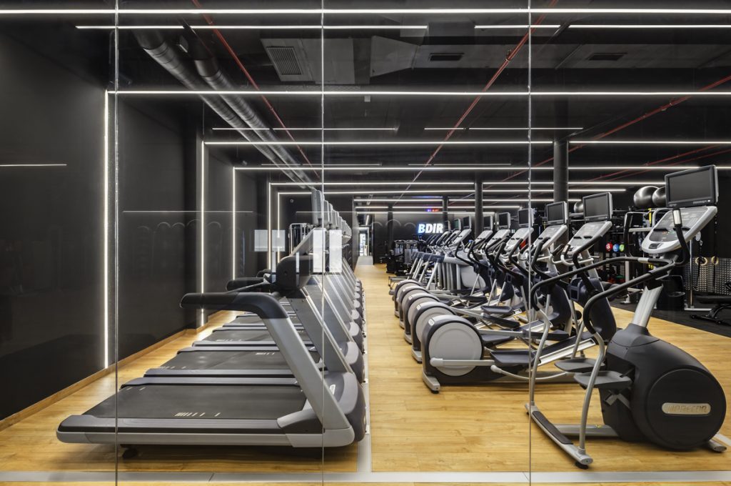 DIR - Studio Shito - Well-lit fitness room with machines and a large mirror