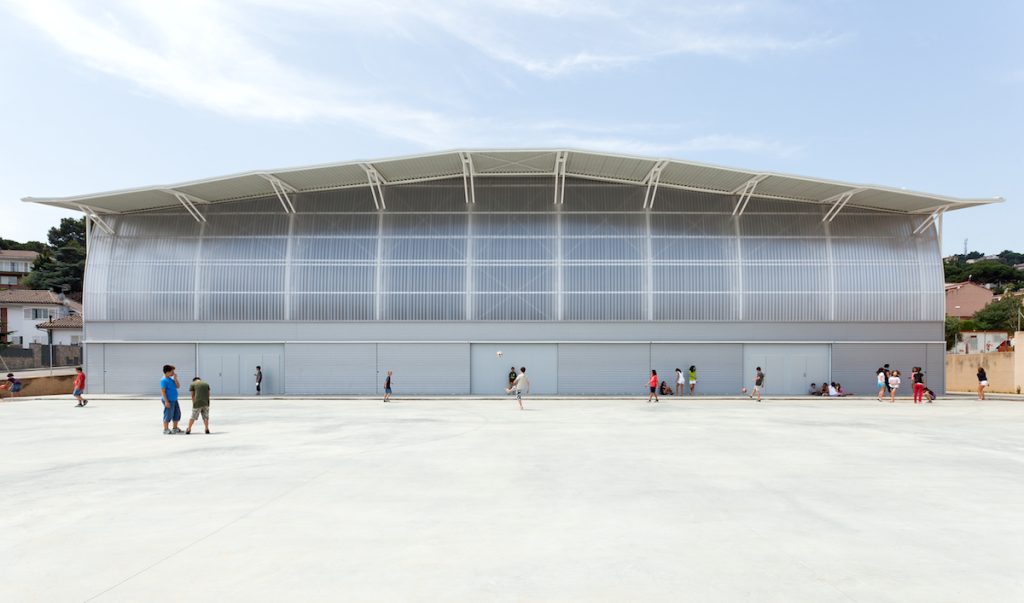 Sports Hall in Cabrils - Soldevila Soldevila Soldevila - Group of people congregating outside a modern building with a distinctive curved roof under a clear sky