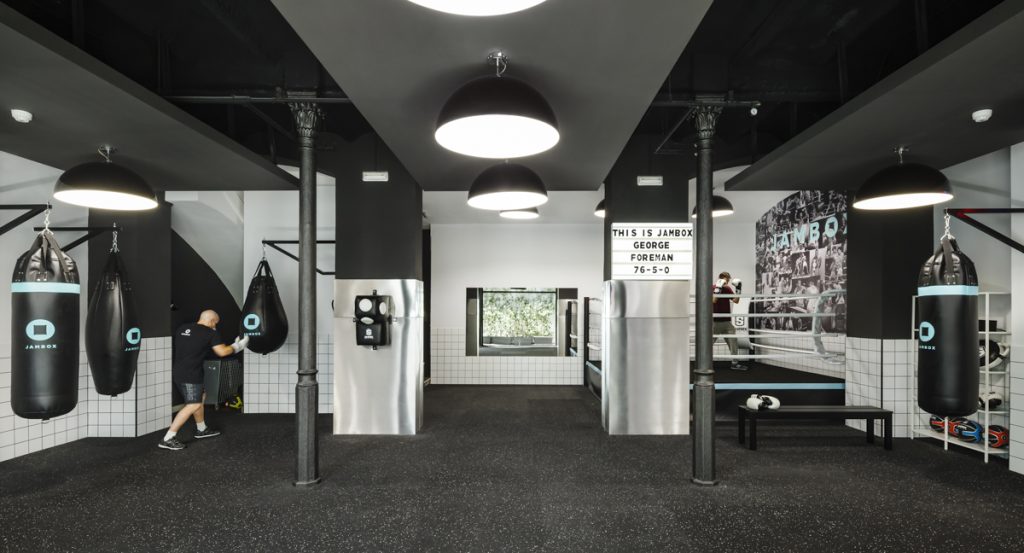 Jambox DIR - WIT Architects - Two people training in a spacious modern boxing room with bags and ring