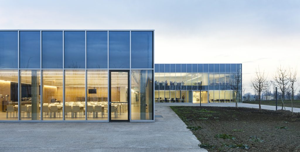 MTA Headquarter - Tommaso Bettini Achitetto - Modern building with large glass panels reflects the evening sky, revealing a well-lit interior