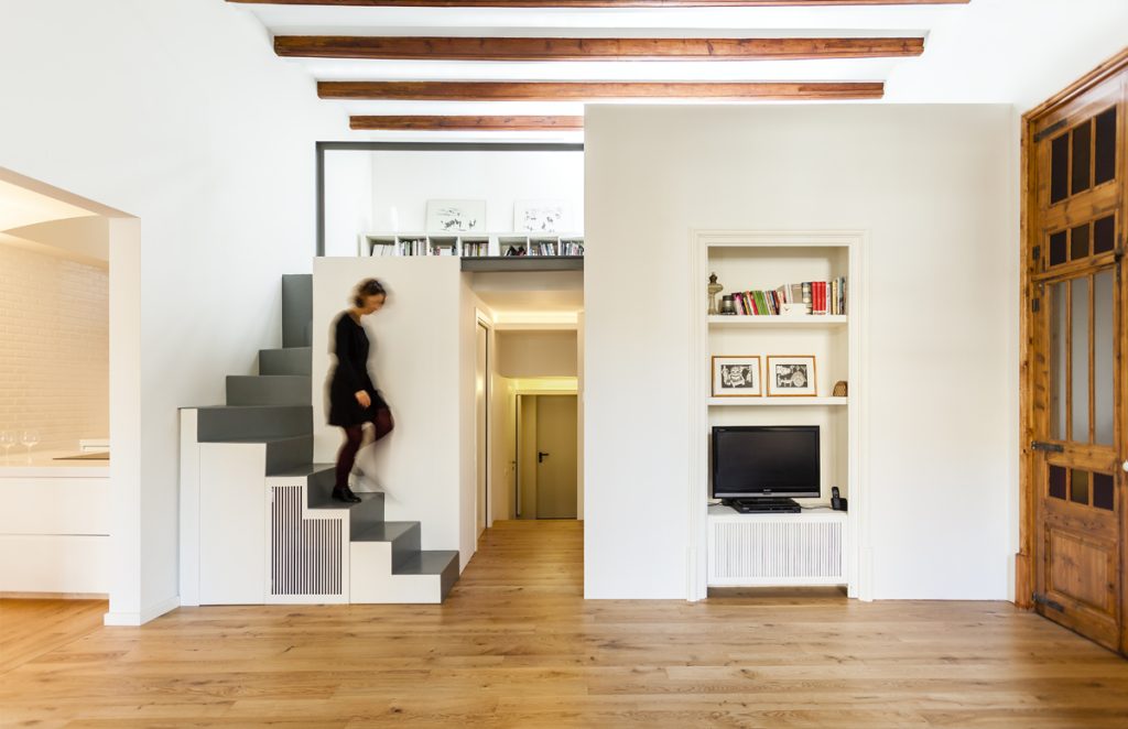 Poblenou Flat - CHPBaiocco Architecture - Person climbs a unique, minimalist staircase in a room blending modern and traditional decor