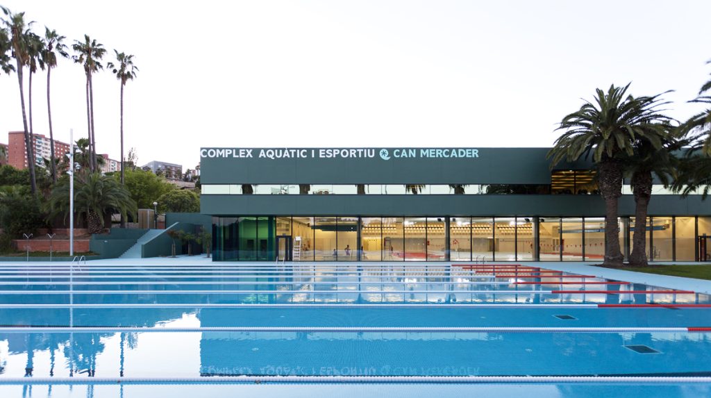 Can Mercader Swimming Pool - RGA Arquitectes - Large greenish modern building with an Olympic swimming pool outside