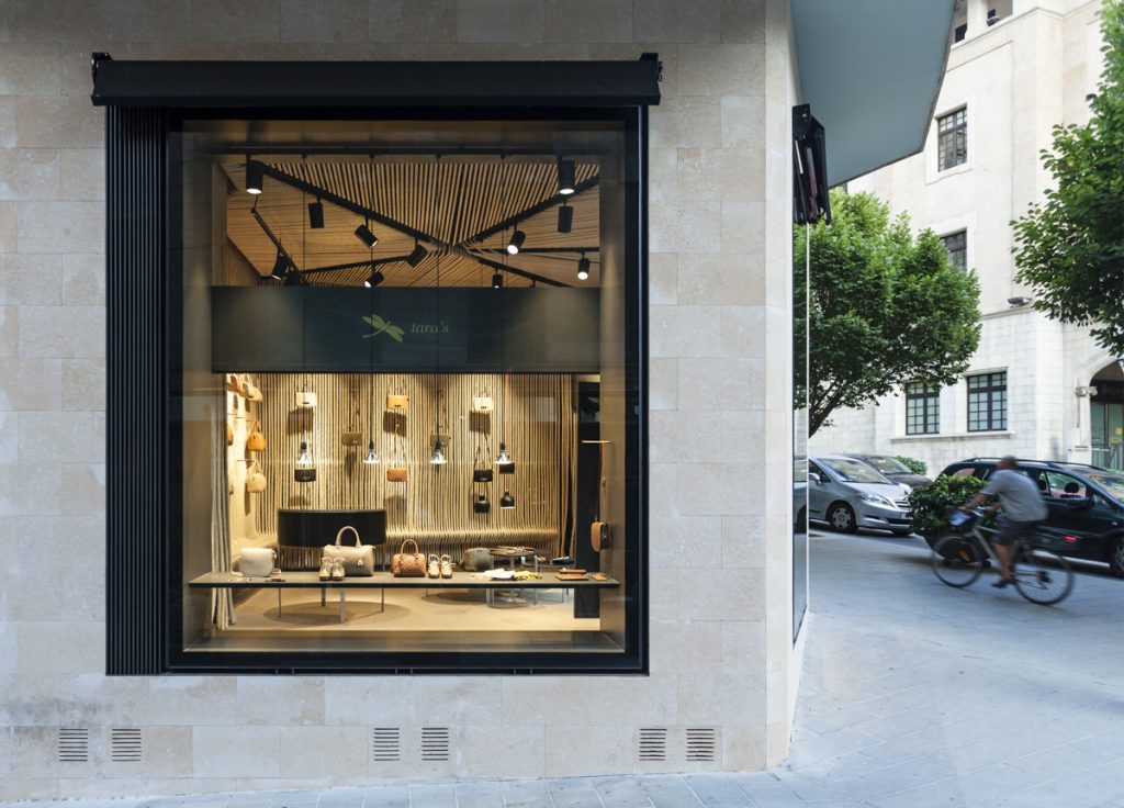 Tara’s Handbag Shop - BAAS Arquitectura - Modern store window, aglow with evening light, showcases a chic display against the city’s tranquil backdrop